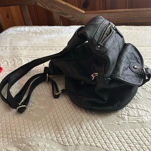 Black pocketbook/backpack made out of man-made materials and silver hardware